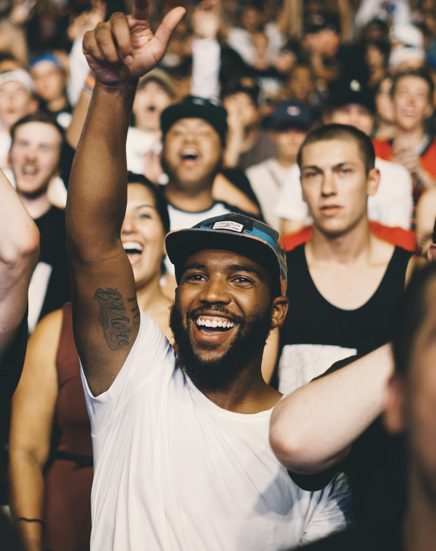 A man in a concert is raising his arm in a crowed and smiling